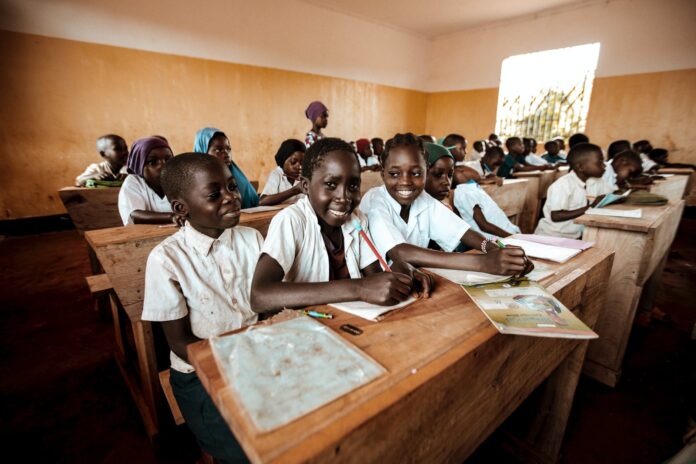 children in classroom with old fashioned wooden desks